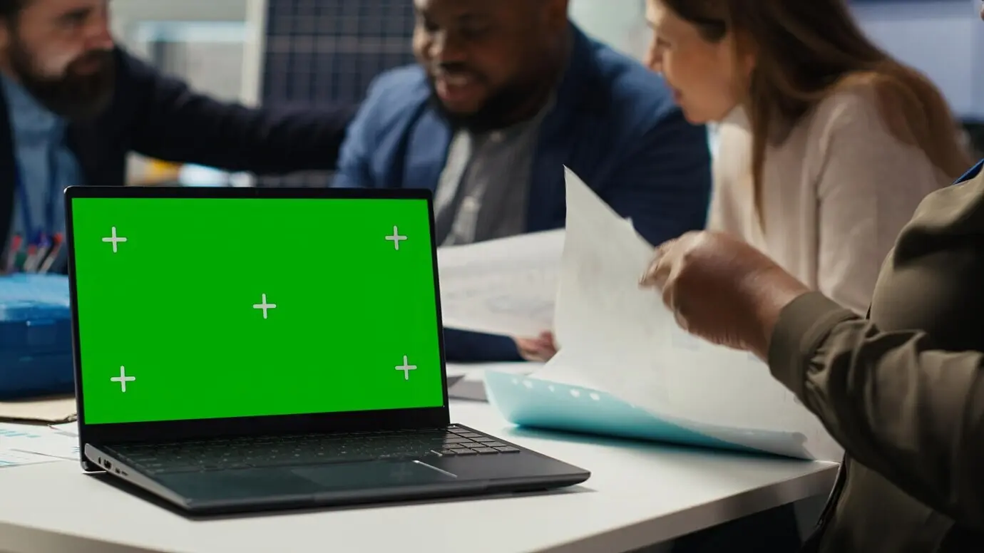 Werksleiter tippt auf einem Laptop mit grünem Bildschirm.